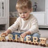 Child playing with wooden letters spelling 'RIVER' in a home setting
